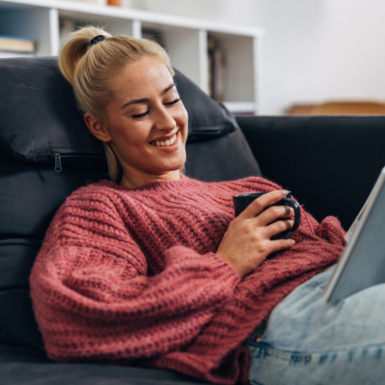 Person reclining on a sofa using a smartphone in a modern Home & Office livingspace.